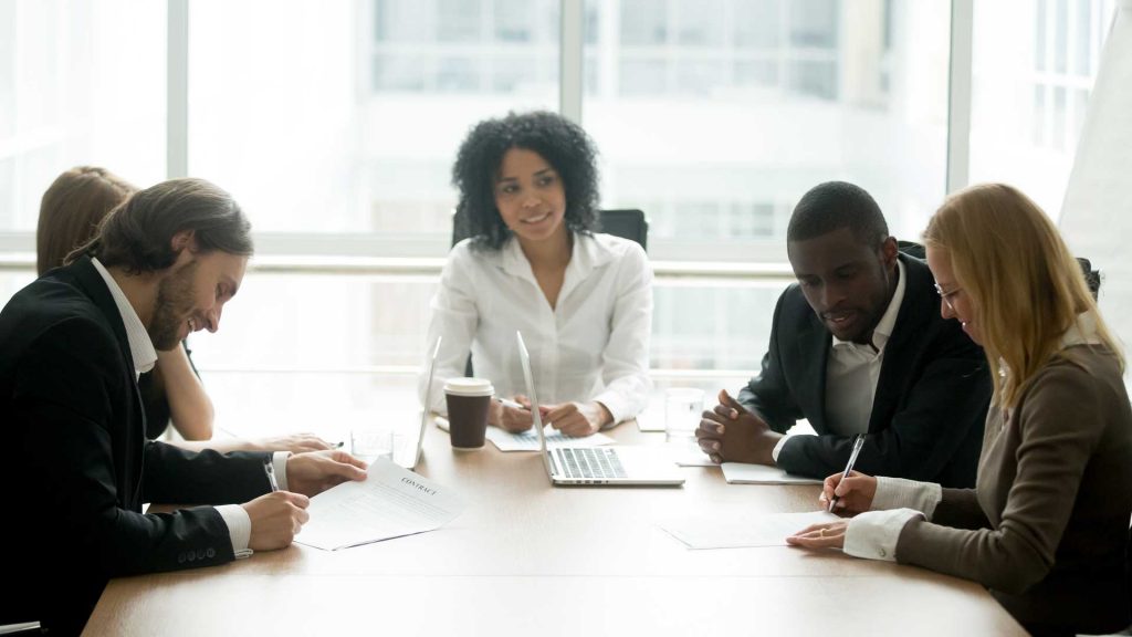 A group of executives work together at a conference table.