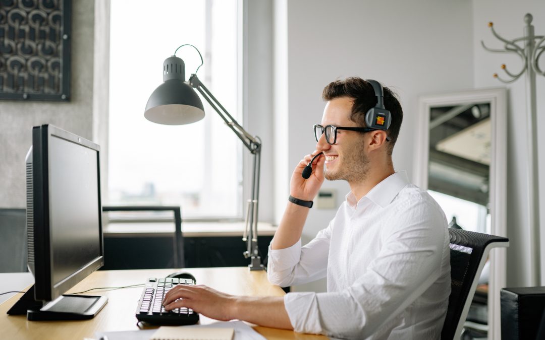 A customer service agent chats ont he phone while he helps a customer.